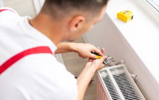 chauffagiste qui répare un radiateur
