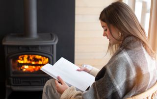 Femme en train de lire devant un poêle