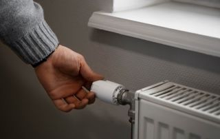 Main réglant la vanne d'un radiateur