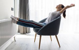 Femme assise sur une chaise avec les pieds sur un radiateur