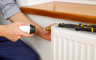 chauffagiste remplaçant la vanne d'un radiateur