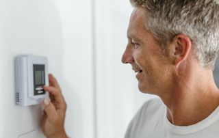 Homme qui règle son thermostat